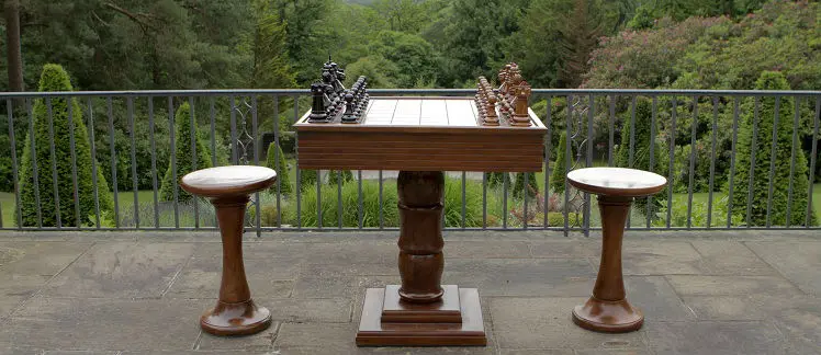 A Wooden Chess Table With Stools and Chess Pieces With forest View